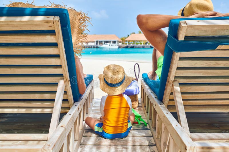 Rodzina przy plażą na drewnianych słońca łóżka loungers obraz stock Rodzina przy plażą na drewnianych słońca łóżka loungers obraz stock