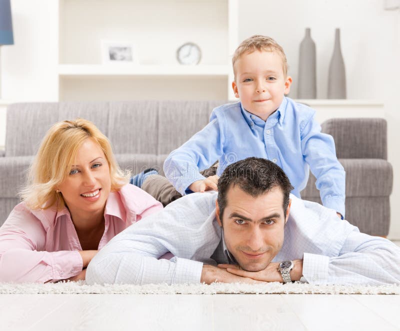 Happy couple and their son lying together on carpet in living room. Happy couple and their son lying together on carpet in living room.