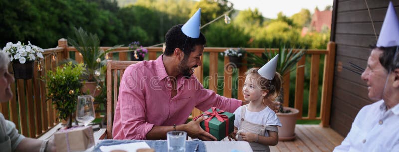 Rodzina wielonarodowa świętująca urodziny i na patio organizuje imprezę ogrodową na podwórku.