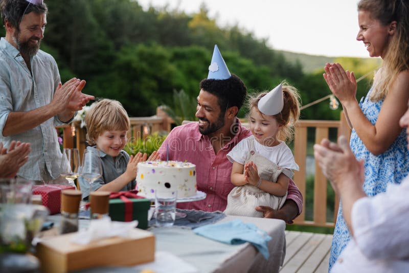 Rodzina wielonarodowa świętująca urodziny i na patio organizuje imprezę ogrodową na podwórku.
