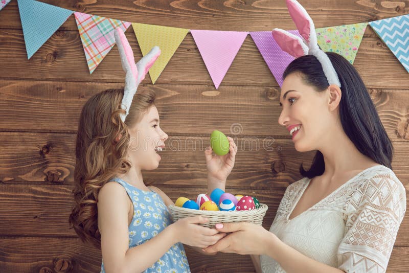 Mother and her daughter with painting eggs. Happy family celebrate Easter. Cute little child girl wearing bunny ears. Mother and her daughter with painting eggs. Happy family celebrate Easter. Cute little child girl wearing bunny ears.