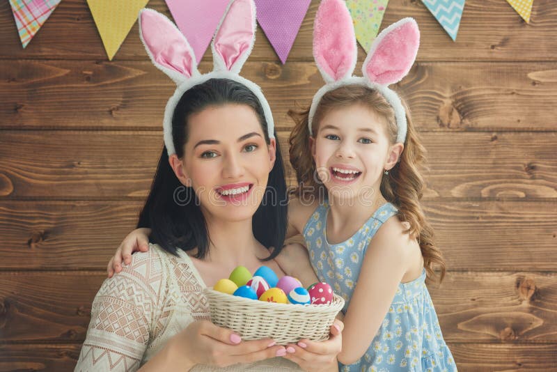 Mother and her daughter with painting eggs. Happy family celebrate Easter. Cute little child girl wearing bunny ears. Mother and her daughter with painting eggs. Happy family celebrate Easter. Cute little child girl wearing bunny ears.