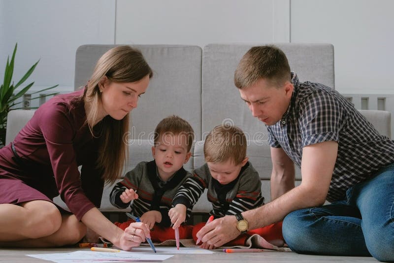 Rodzinna mama, tata i dwa brat bliźniak, rysujemy wpólnie markierów i filc pisze obsiadanie na podłoga fotografia royalty free Rodzinna mama, tata i dwa brat bliźniak, rysujemy wpólnie markierów i filc pisze obsiadanie na podłoga fotografia royalty free