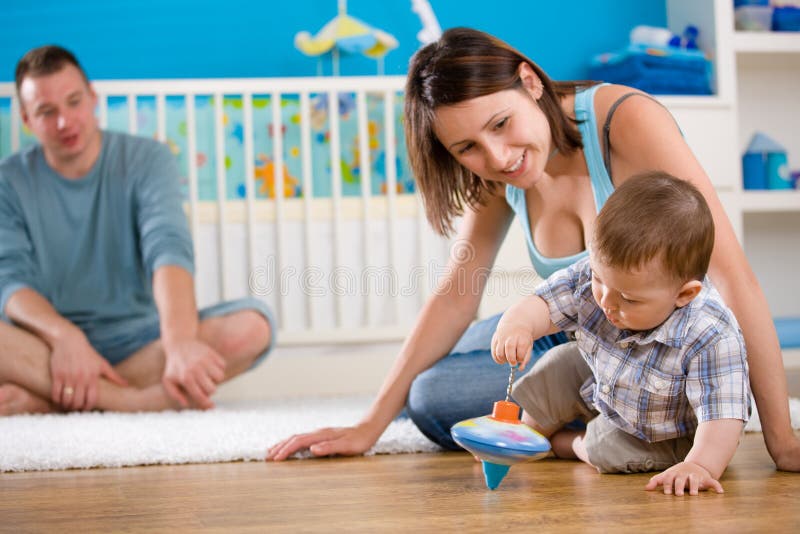 Portrait of happy family at home. Baby boy ( 1 year old ) and young parents father and mother sitting on floor and playing together at children's room, smiling. Portrait of happy family at home. Baby boy ( 1 year old ) and young parents father and mother sitting on floor and playing together at children's room, smiling.