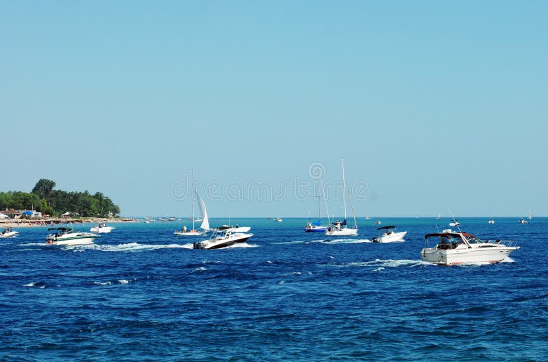 Power boats and sailboats on a busy lake with blue sky. Power boats and sailboats on a busy lake with blue sky