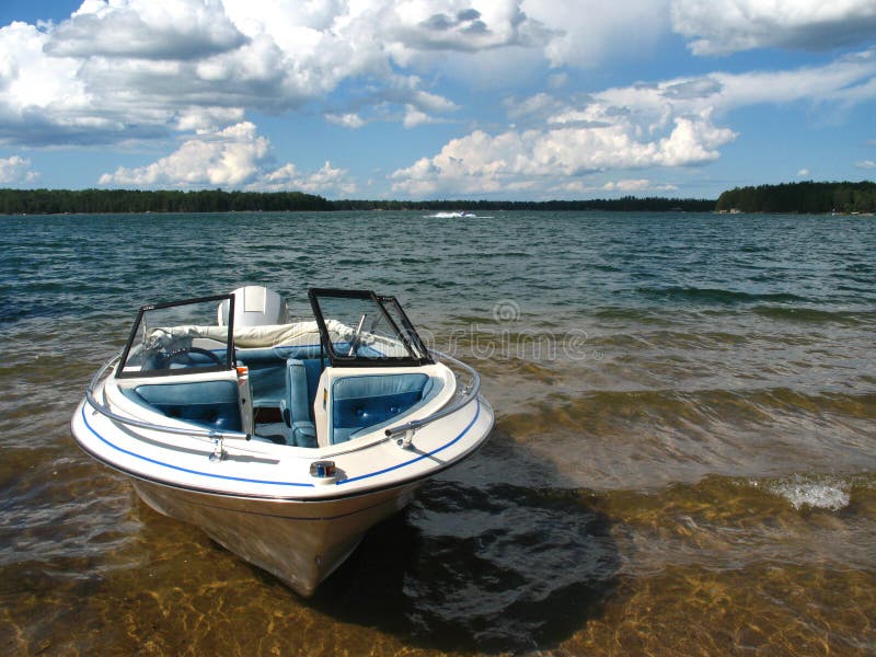 A boat rests on the shore of a lake. A boat rests on the shore of a lake.