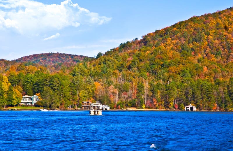 A pontoon boat on a mountain lake surrounded by fall foliage. Lake Burton in north Georgia. A pontoon boat on a mountain lake surrounded by fall foliage. Lake Burton in north Georgia.