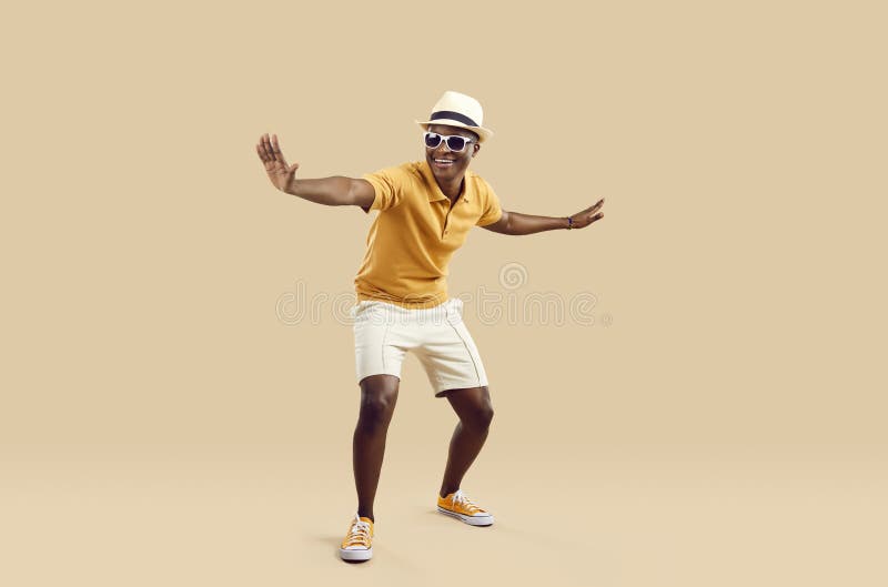 Roemrijk , stijlvol , afrikaans - amerikaans man met plezier dansen op lichtbeige achtergrond.