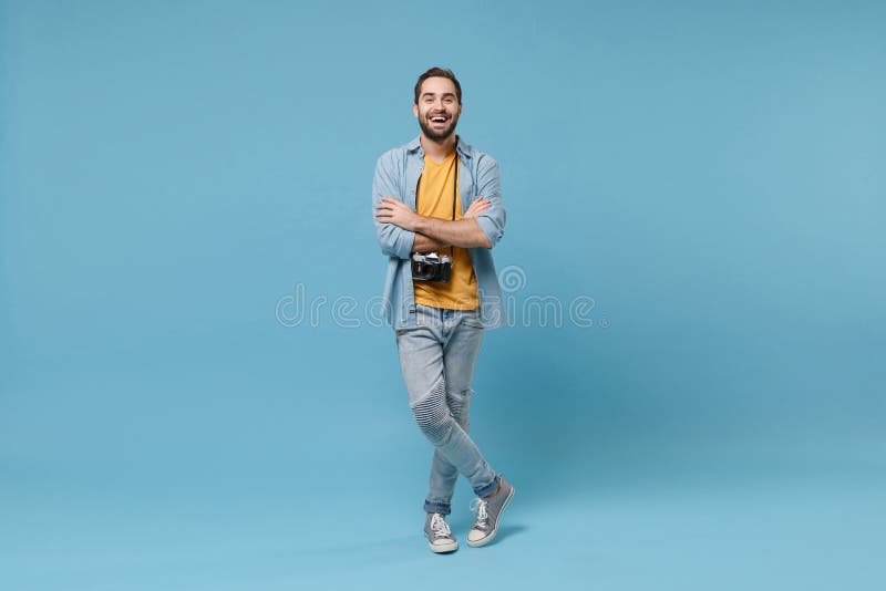 Cheerful traveler tourist man in casual summer clothes with photo camera isolated on blue background. Male passenger traveling abroad on weekends. Air flight journey concept. Holding hands crossed. Cheerful traveler tourist man in casual summer clothes with photo camera isolated on blue background. Male passenger traveling abroad on weekends. Air flight journey concept. Holding hands crossed