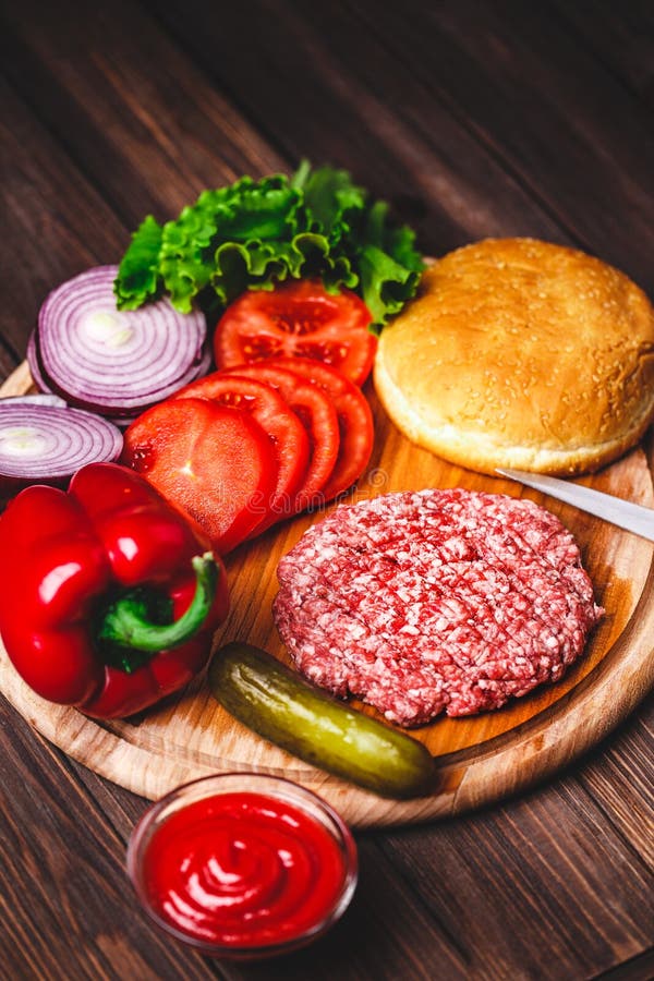 Rohe Rinderhackfleischfleisch Burger-Steakkoteletts mit Gew?rz, K?se, Tomaten, Salat und Br?tchen auf h?lzernen Brettern der Wein lizenzfreie stockbilder Rohe Rinderhackfleischfleisch Burger-Steakkoteletts mit Gew?rz, K?se, Tomaten, Salat und Br?tchen auf h?lzernen Brettern der Wein lizenzfreie stockbilder
