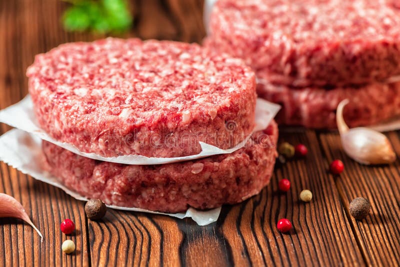 Rohe Rindfleischfleischburger-Steakkoteletts, trockener Pfeffer und Knoblauch auf RUR lizenzfreie stockbilder Rohe Rindfleischfleischburger-Steakkoteletts, trockener Pfeffer und Knoblauch auf RUR lizenzfreie stockbilder