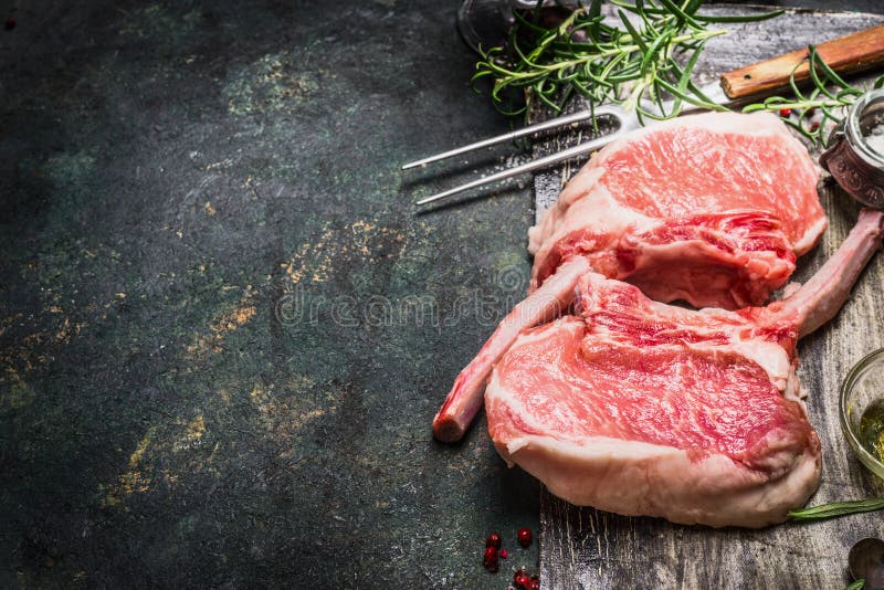 Rohes feinschmeckerisches Schweinefleischkotelett für Grill, Grill oder das Kochen mit Kräutern, Gewürze und Fleisch gabeln auf d stockbilder Rohes feinschmeckerisches Schweinefleischkotelett für Grill, Grill oder das Kochen mit Kräutern, Gewürze und Fleisch gabeln auf d stockbilder