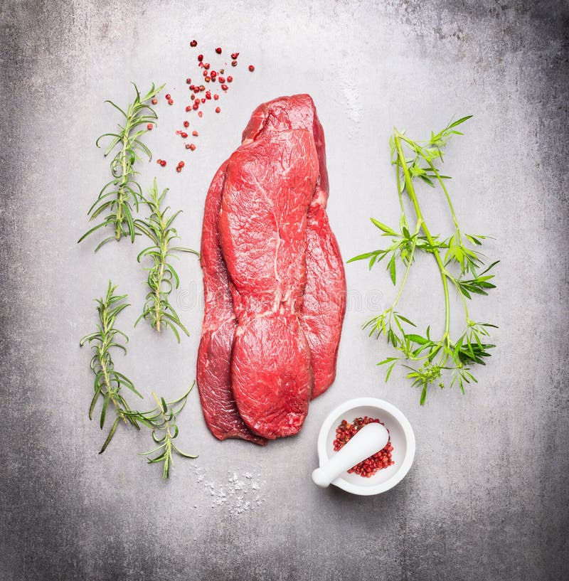 Rohes Rindfleischfleischsteak mit frischen Kräutern auf grauem Steinhintergrund lizenzfreie stockfotografie