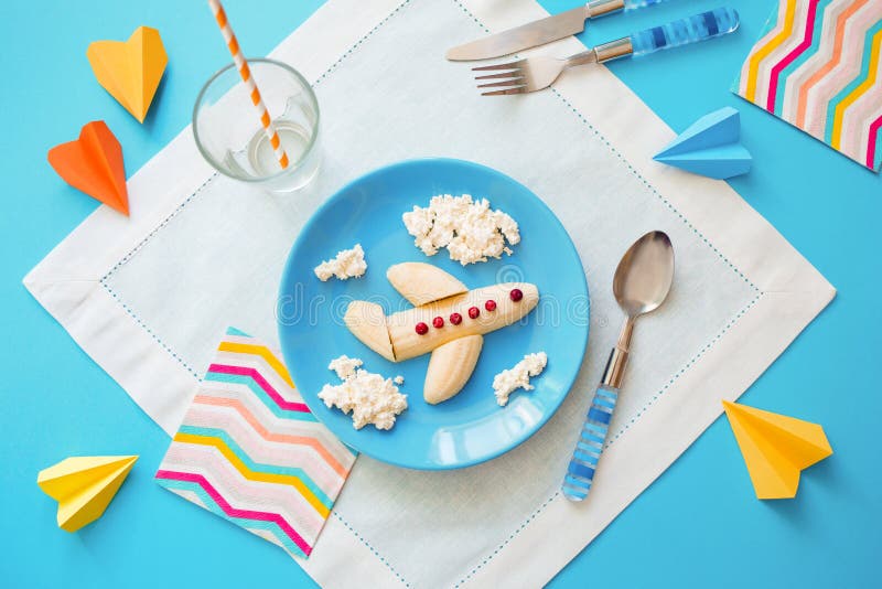 Rolig matid? f?r ungar barns frukost: nivå som göras av bananen och moln som göras av ostmassa på en blå platta fotografering för bildbyråer Rolig matid? f?r ungar barns frukost: nivå som göras av bananen och moln som göras av ostmassa på en blå platta fotografering för bildbyråer