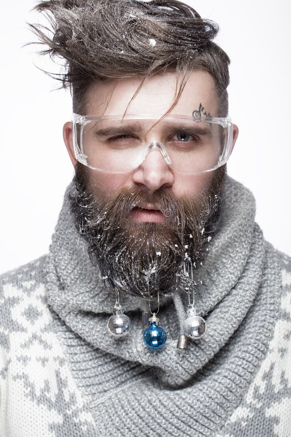 Rolig skäggig man i en bild för ` s för nytt år med snö och garneringar på hans skägg Festmåltid av jul royaltyfri fotografi Rolig skäggig man i en bild för ` s för nytt år med snö och garneringar på hans skägg Festmåltid av jul royaltyfri fotografi