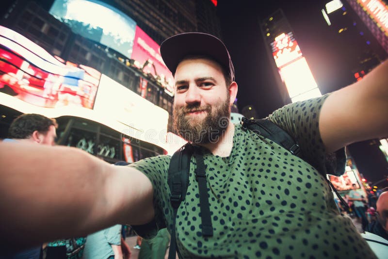 Rolig skäggig manfotvandrare som ler och tar selfiefotoet på Times Square i New York medan lopp över USA fotografering för bildbyråer Rolig skäggig manfotvandrare som ler och tar selfiefotoet på Times Square i New York medan lopp över USA fotografering för bildbyråer