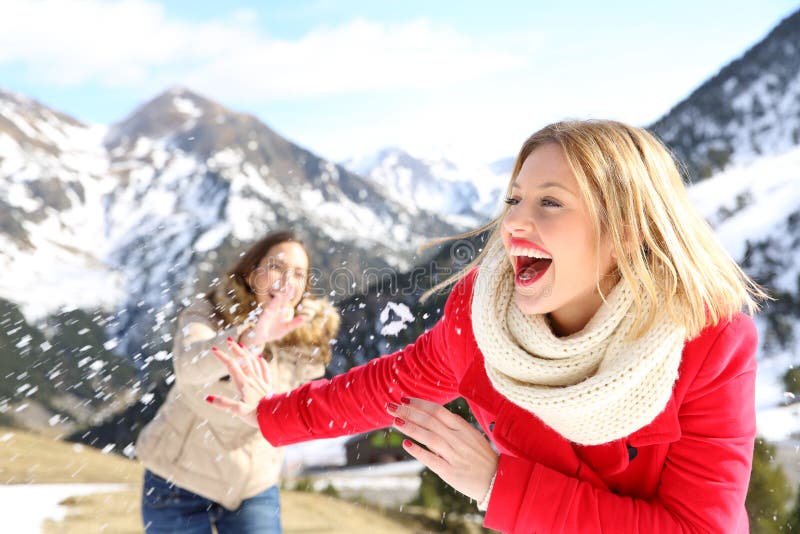 Two funny friends joking throwing snowballs in the mountain on winter holiday. Two funny friends joking throwing snowballs in the mountain on winter holiday