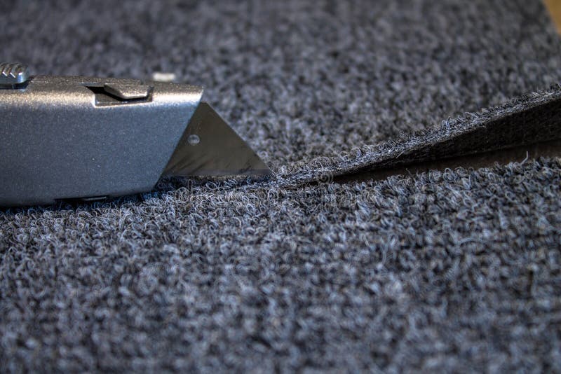 Grey roll of carpet and a knife for slicing royalty free stock images