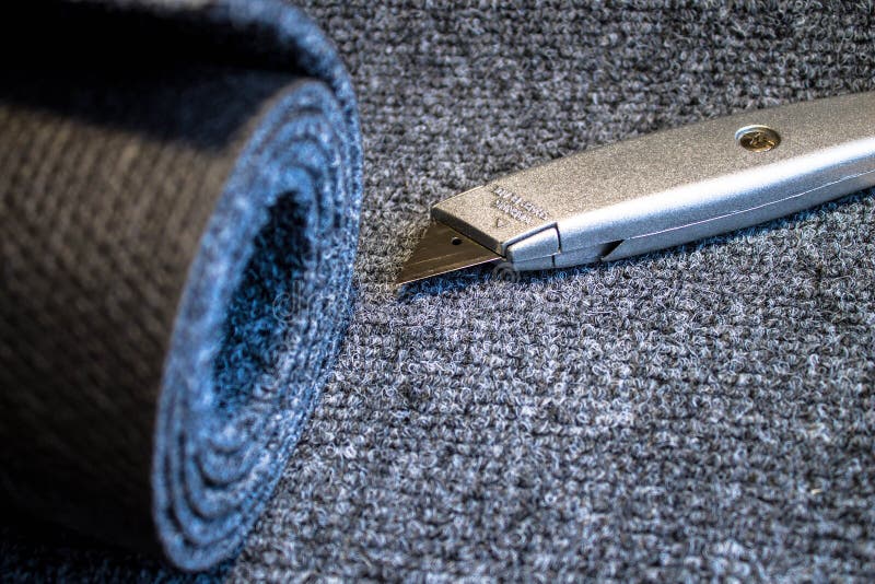 Grey roll of carpet and a knife for slicing stock image