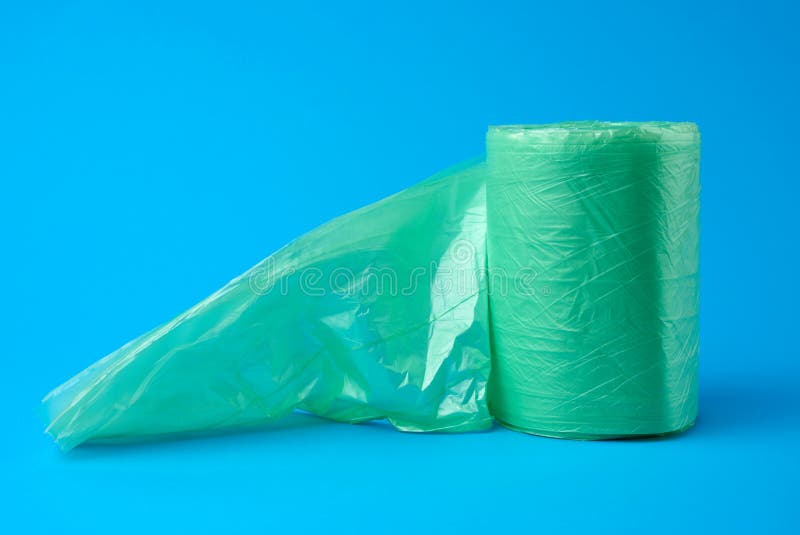 Roll Green Plastic Bags for Trash Bin on Blue Background Stock Photo