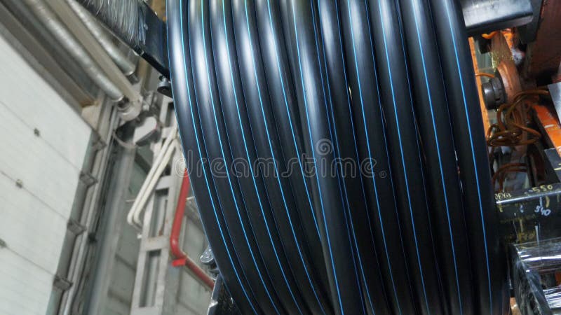 Roll threading coil pipe. Manufacture of plastic water pipes factory. Process of making plastic tubes on the machine royalty free stock photography