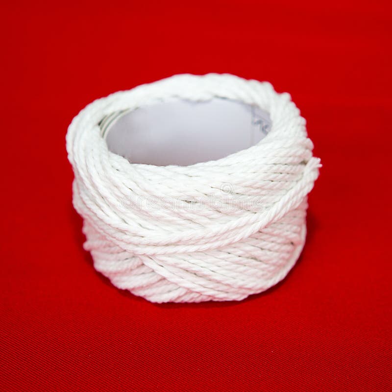 Roll of white string on a red fabric.