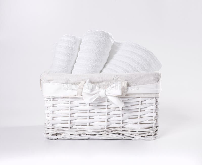 Rolled white soft terry towels in the basket against a white backdrop. Striped towels in a white basket in front of a white royalty free stock images