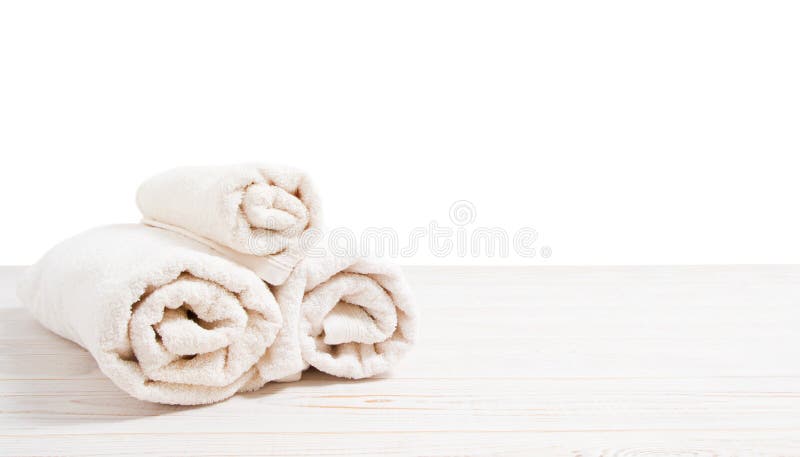 Rolled white towels on white wooden table  on white background. Copy space and top view. Bathroom objects for shower body