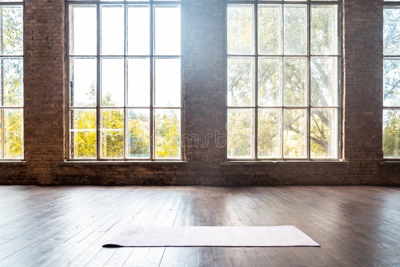 Rolled yoga pilates rubber mat inside gym studio on wooden floor background