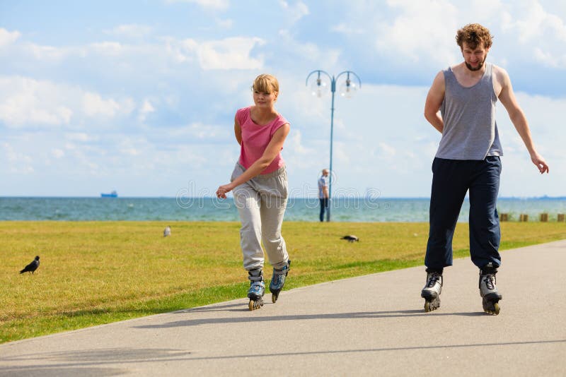 Rollerblades молодых пар ехать в парке стоковые изображения Rollerblades молодых пар ехать в парке стоковые изображения