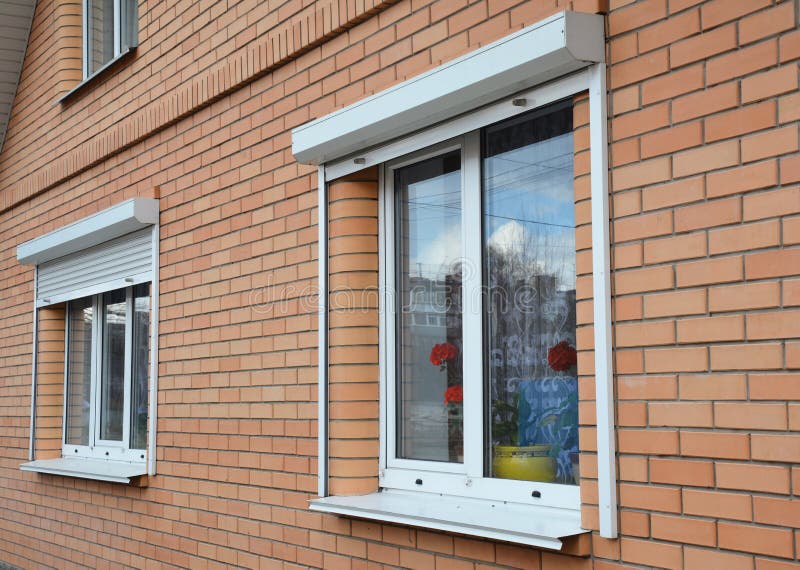 Rolling shutters house windows protection. Brick house with metal roller shutters on the windows