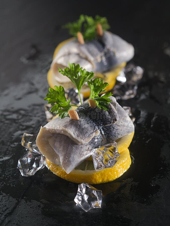 Rollmop herring on lemon slices and ice cubes