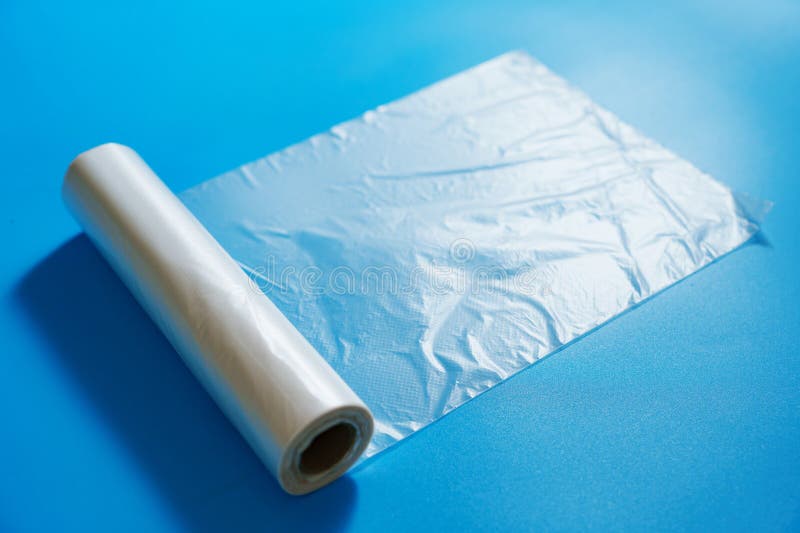 Rollo de bolsas transparentes de embalaje en un fondo azul. almacenamiento y envasado de productos en el hogar.
