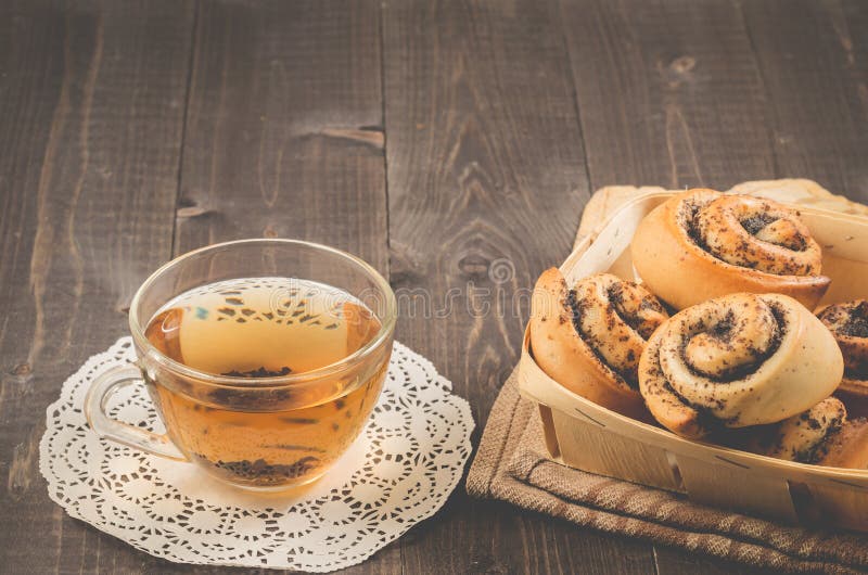 Rollos del whith del desayuno con la amapola y el té de cristal del whith de la taza/rollos del whith del desayuno con la amapola fotografía de archivo Rollos del whith del desayuno con la amapola y el té de cristal del whith de la taza/rollos del whith del desayuno con la amapola fotografía de archivo