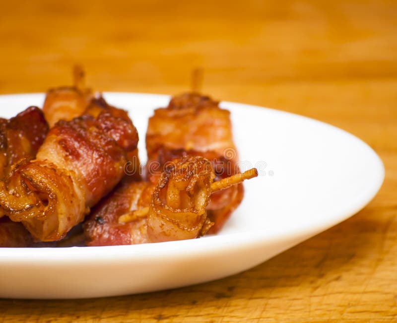 Rolls delle fette di oggetto cucinato del bacon con gli stuzzicadenti su un wh fotografie stock Rolls delle fette di oggetto cucinato del bacon con gli stuzzicadenti su un wh fotografie stock