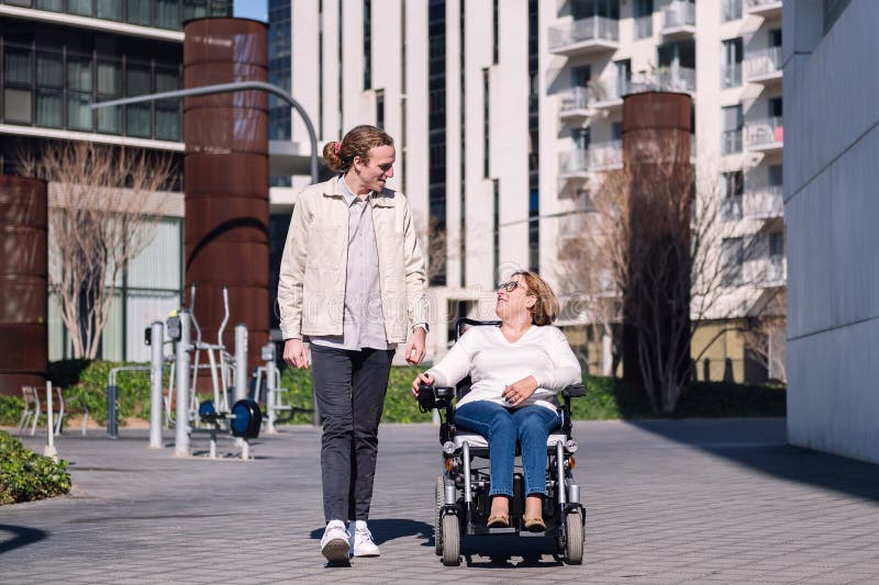 Rollstuhlfahrer mit Frau durch die Stadt stockbild