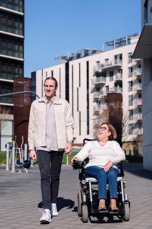 Rollstuhlfahrer mit Frau durch die Stadt stockfotos