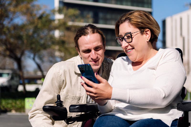 Rollstuhlfahrerin, die einem Freund das Telefon zeigt lizenzfreies stockbild