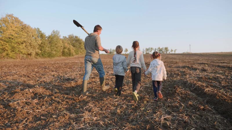 Rolnik z jego cztery dziećmi iść na rolnym polu dla pracy wpólnie