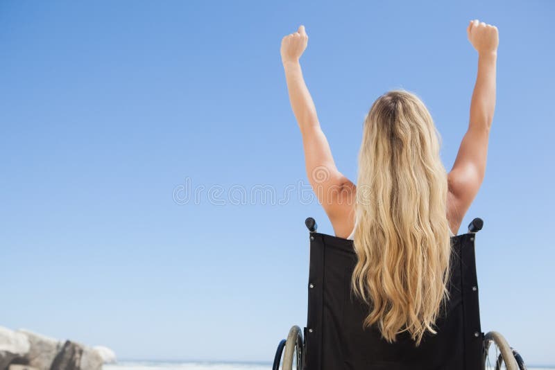 Rolstoel verbindende blondezitting op het strand met omhoog wapens stock afbeeldingen Rolstoel verbindende blondezitting op het strand met omhoog wapens stock afbeeldingen