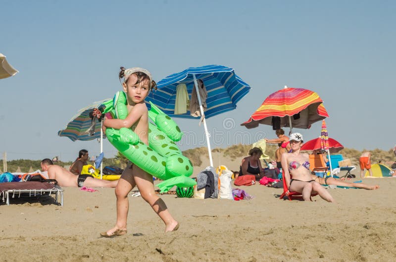 ROMA, ITALY - JULY 2017: Little charming girl playing on a sandy beach with an inflatable circle with a girlfriend and swimming in royalty free stock photo ROMA, ITALY - JULY 2017: Little charming girl playing on a sandy beach with an inflatable circle with a girlfriend and swimming in royalty free stock photo