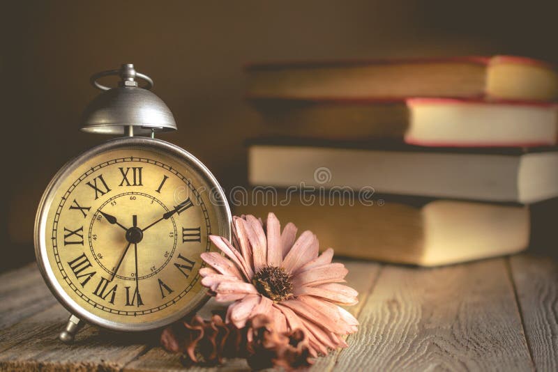 Roman Numeral in Vintage Alarm Clock and Stack of Book Background stock image