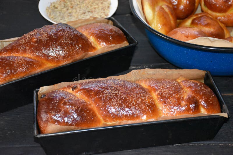 Romanian traditional Cozonac sweet bread in trays on a wooden black table with Turkish delight, nuts and bun bread in a