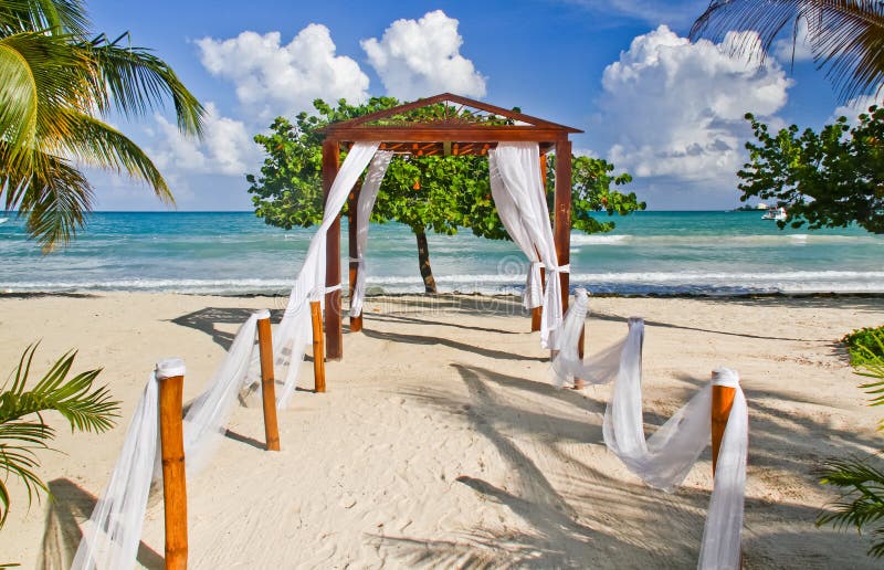 Vista del Mar dei Caraibi, in lontananza, attraverso un bel lato della spiaggia, pergolato arredato come un luogo di nozze del Couples Negril resort a Negril, in Giamaica.