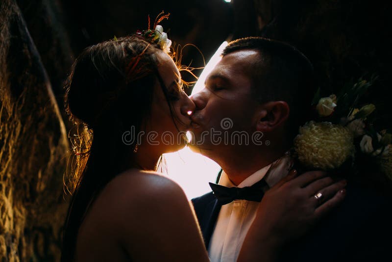 Romantic beautiful bride and elegant stylish groom kissing, backgrounded by sunset shining. Close-up stock photos Romantic beautiful bride and elegant stylish groom kissing, backgrounded by sunset shining. Close-up stock photos