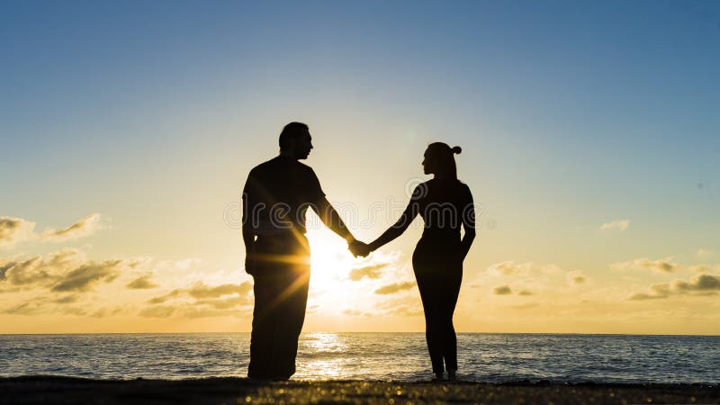 Romantic couple on the beach at colorful sunset on background stock image Romantic couple on the beach at colorful sunset on background stock image