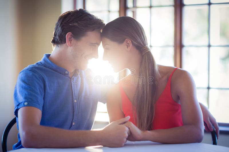 Romantic Couple Holding Hands And Sitting Face To Face Stock I