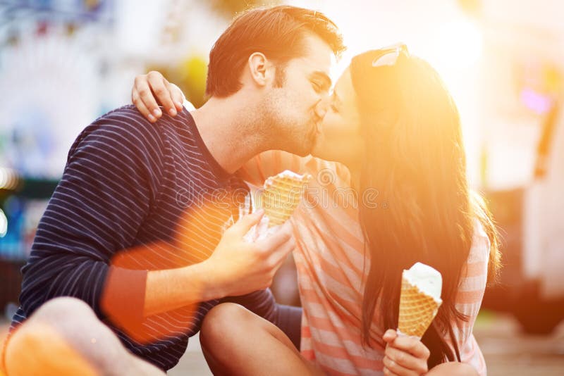 Foto di una romantica coppia che si bacia mentre si tiene premuto il gelato.