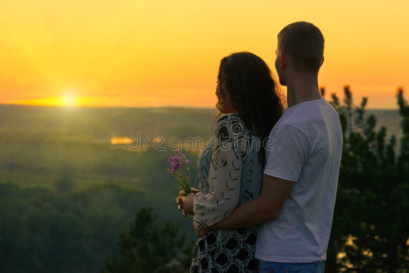 Romantic couple look on sunset on country outdoor, beautiful landscape and bright yellow sky, love tenderness concept, young adult people. Romantic couple look on sunset on country outdoor, beautiful landscape and bright yellow sky, love tenderness concept, young adult people