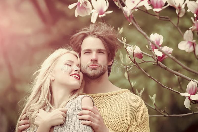 Romantic couple in love in spring garden at beautiful blooming magnolia tree.